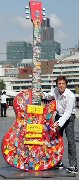 Sir Paul McCartney and his 10 foot hand painted Gibson Les Paul on site at the Gibson Guitartown London charity exhibition